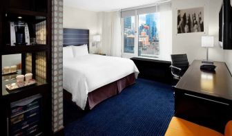 King bedroom with TV, work station and a view of the city at Hilton New York Fashion District.
