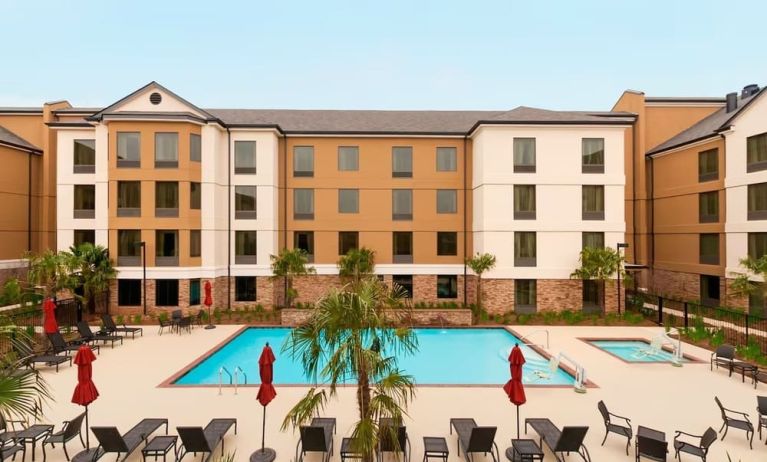 Outdoor pool with lounge chairs at Homewood Suites By Hilton Shreveport / Bossier City, LA.