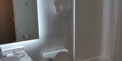 Guest bathroom with shower and tub at Hotel Key.