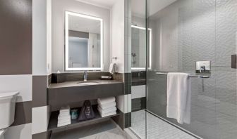 Private guest bathroom with shower and free toiletries at The Rose Hotel Chicago O’Hare, Tapestry Collection By Hilton.