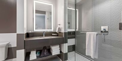 Private guest bathroom with shower and free toiletries at The Rose Hotel Chicago O’Hare, Tapestry Collection By Hilton.