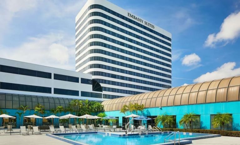 Outdoor pool with lounge chairs at Embassy Suites By Hilton West Palm Beach Central.