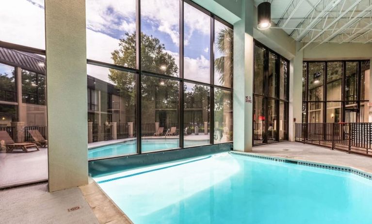 Combined indoor-outdoor pool with lounge seating at Red Roof PLUS+ & Suites Houston - IAH Airport SW.