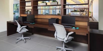 Business center with computers, printer and ergonomic chairs at Element Miami International Airport.
