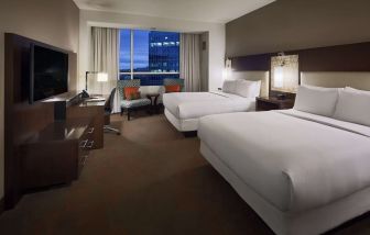 Day use twin room with workspace and lounge seating at Hilton Dallas/ Plano Granite Park.