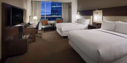 Day use twin room with workspace and lounge seating at Hilton Dallas/ Plano Granite Park.