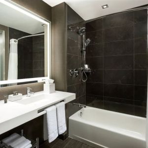 Private guest bathroom with combined shower and tub at AC Hotel New York Times Square.
