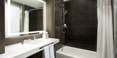 Private guest bathroom with combined shower and tub at AC Hotel New York Times Square.