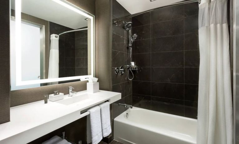 Private guest bathroom with combined shower and tub at AC Hotel New York Times Square.