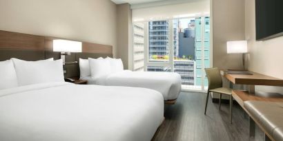 Day use twin room with workspace, floor to ceiling window and private bathroom at AC Hotel New York Times Square.