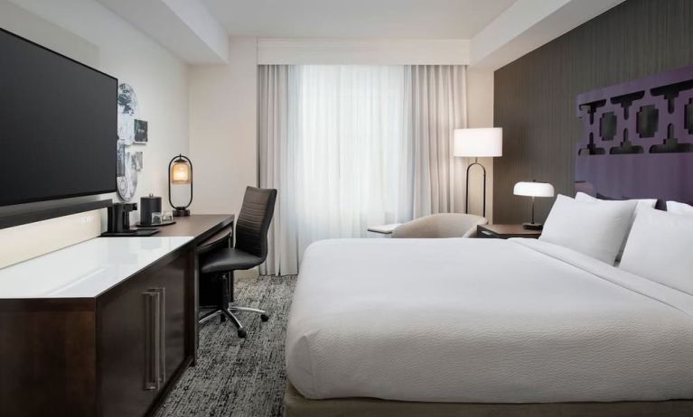 Delux king room with TV, work desk, and natural light at Courtyard San Diego Downtown.