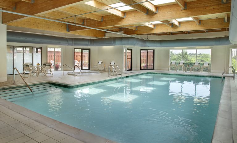 Relaxing indoor pool with lounge chairs at Courtyard By Marriott Toronto Airport.