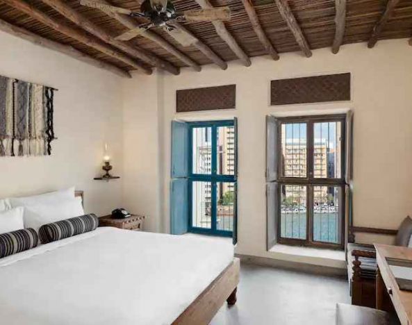 Bright room with king size bed, desk and windows at the Al Seef Heritage Hotel Dubai, Curio Collection by Hilton.