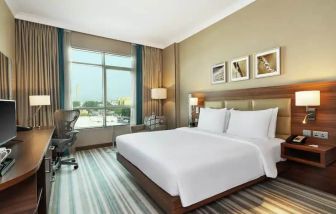 Comfortable King room with king bed, desk, tv and living room area at the Hilton Garden Inn Dubai Al Mina