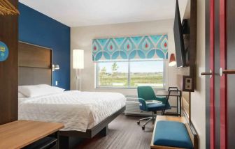 Clean king sized bed with TV and work area at Tru by Hilton Milwaukee Brookfield.