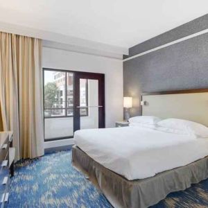 King size bed, large window and TV screen in a king room at the Embassy Suites by Hilton Alexandria-Old Town.