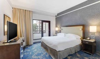 King size bed, large window and TV screen in a king room at the Embassy Suites by Hilton Alexandria-Old Town.