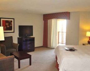 delux king-sized bed with lounge area and TV at Hampton Inn & Suites Phoenix/Gilbert, AZ.