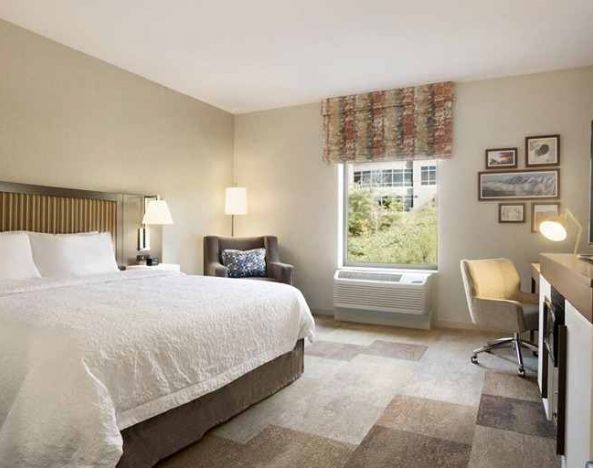 bright-lit king-sized bed with TV and work desk at Hampton Inn Salt Lake City Cottonwood.