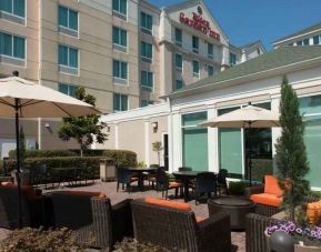 Outdoor patio area with lounges and tables perfect as workspace at the Hilton Garden Inn Tallahassee Central.