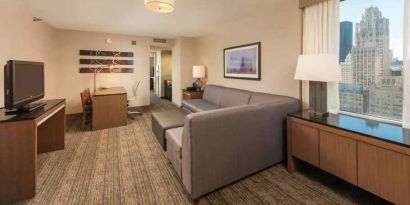 Spacious living room with working station in a king suite at the Embassy Suites by Hilton Chicago Magnificent Mile.