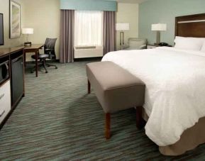 Comfortable king bedroom with TV screen and desk at the Hampton Inn & Suites Schererville.