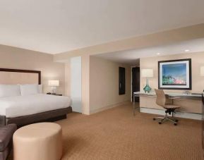 King size bed, desk and sofa in a spacious hotel room at the at the Hilton Miami Airport Blue Lagoon.