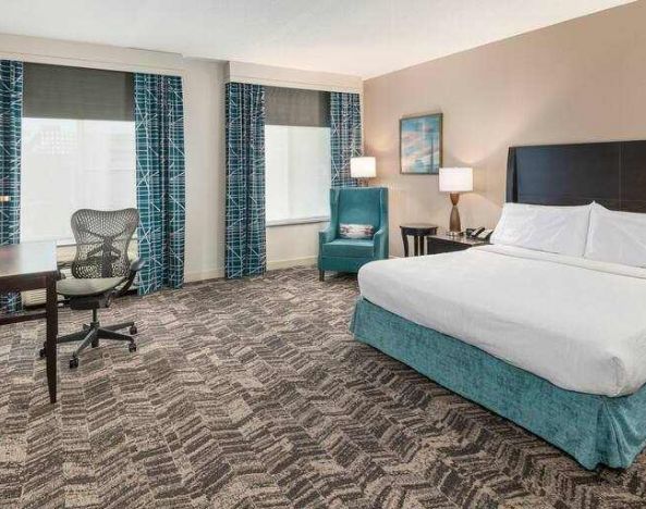 King size bed, sofa and desk in a hotel room at the Hilton Garden Inn Silver Spring White Oak.