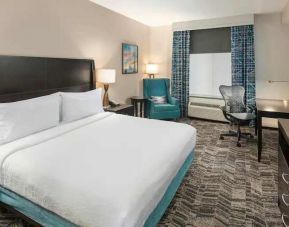 Comfortable hotel guestroom with king size bed and working station at the Hilton Garden Inn Silver Spring White Oak.