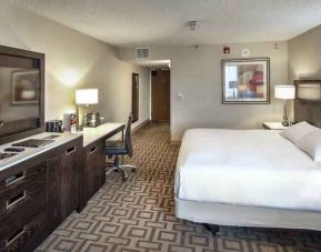 TV screen, desk and sofa in a king suite at the Hilton Sacramento-Arden West.