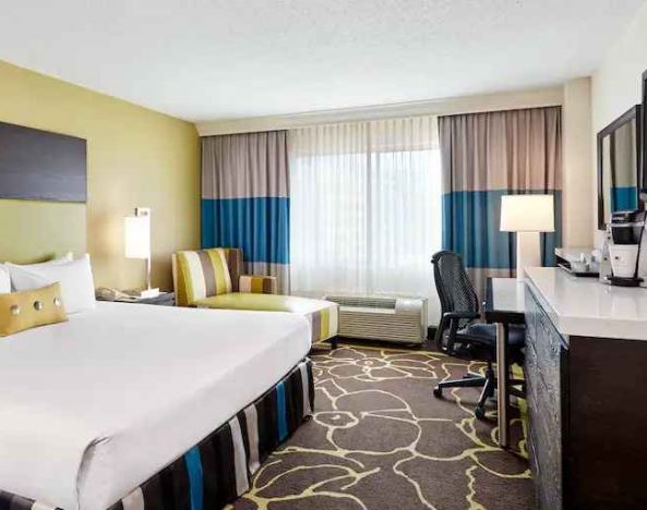 Bright king guestroom with king size bed, sofa and desk at the DoubleTree by Hilton Charlotte-Gateway Village.