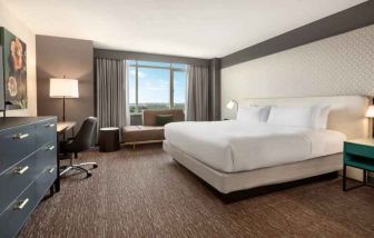 King guestroom with TV screen, desk and window at the Hilton Baltimore BWI Airport.