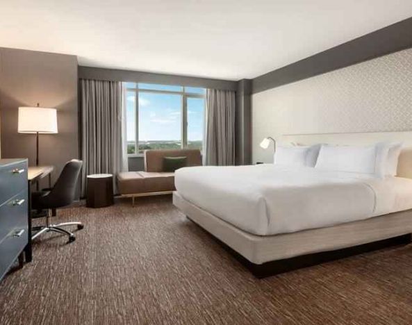 King guestroom with TV screen, desk and window at the Hilton Baltimore BWI Airport.