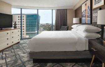King size bed, TV screen and large window in a hotel room at the Embassy Suites by Hilton San Francisco Airport.