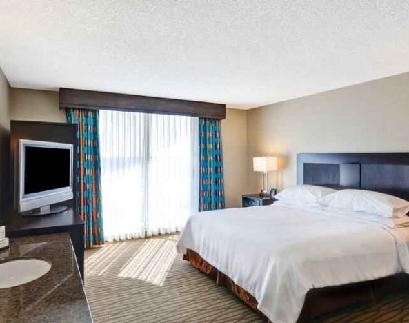 King bedroom with TV screen and window at the Embassy Suites by Hilton Miami - International Airport.