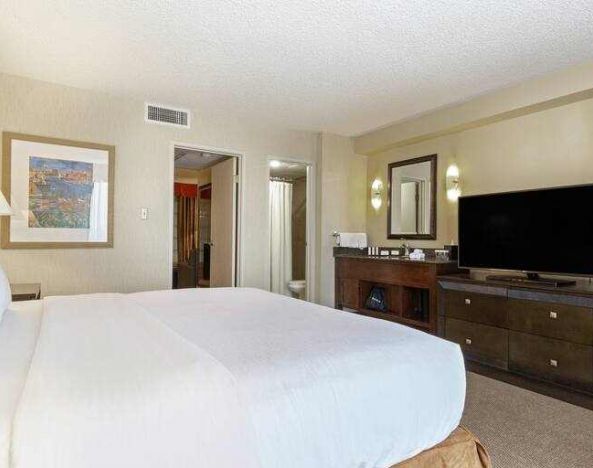 Comfortable king bedroom in a hotel suite at the Embassy Suites by Hilton Kansas City Plaza.