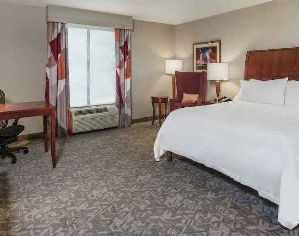 King size bed and desk in a hotel bedroom at the Hilton Garden Inn Blacksburg University.