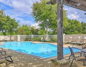 beautiful outdoor pool surrounded by greenery and with comfortable seating area at Hampton Inn & Suites Schertz.