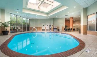 Bright-lit indoor pool with sun roof and comfortable seating area at Embassy Suites by Hilton Seattle Tacoma International Airport.