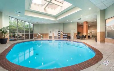 Bright-lit indoor pool with sun roof and comfortable seating area at Embassy Suites by Hilton Seattle Tacoma International Airport.