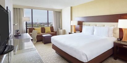 Bright king bedroom with sofa, window and desk at the DoubleTree by Hilton Washington DC - Crystal City.