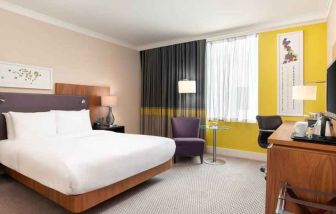King guestroom with desk and TV screen at the Hilton London Wembley.