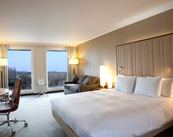 King guestroom with desk and sofa at the Hilton London Heathrow Airport Terminal 5.