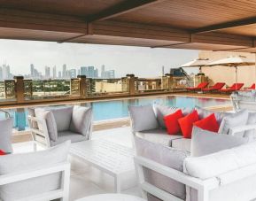 Rooftop pool with seating overlooking a city view at the Hilton Dubai Al Jadaf.