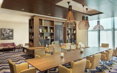 Bronze eclectic lighting hangs over long wooden table lined with floor to ceiling bookshelves.