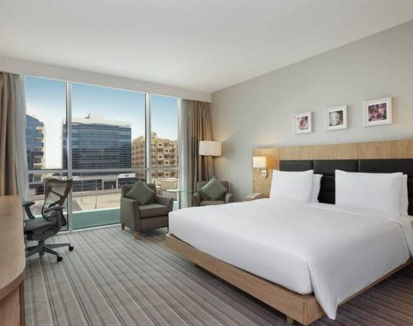 King-sized bed with view of city buildings at the Hilton Garden Inn Dubai Mall of the Emirates.