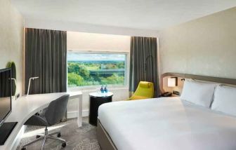 King bedroom with desk and window at the Hilton London Heathrow Airport.