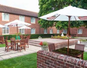 Outdoor patio with chairs, tables and sun umbrellas at the DoubleTree by Hilton Newbury North.