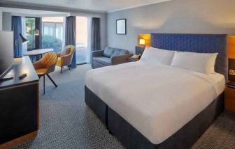 Bright king bedroom with windows and desk at the DoubleTree by Hilton Manchester Airport.
