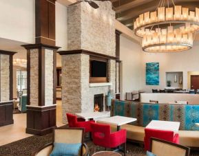 Colorful chairs and booths to eat, socialize or work at. Bright spacious area with large fireplace and chandelier overhead.